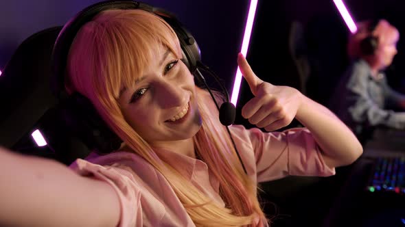 Indoor Shot of a Blonde Cute Gamer Girl with Blonde Hair and a Fringe Wearing a Head Set with a Mic