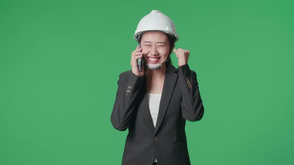 Asian Female Engineer Talking On Smartphone And Celebrating While Walking In The Green Screen