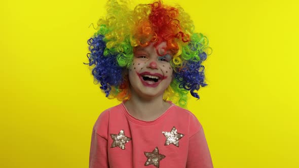 Little Child Girl Clown in Rainbow Wig Making Silly Faces. Having Fun, Smiling, Laughing. Halloween