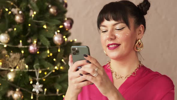 Festive beautiful woman typing message on mobile phone texting sms congratulates