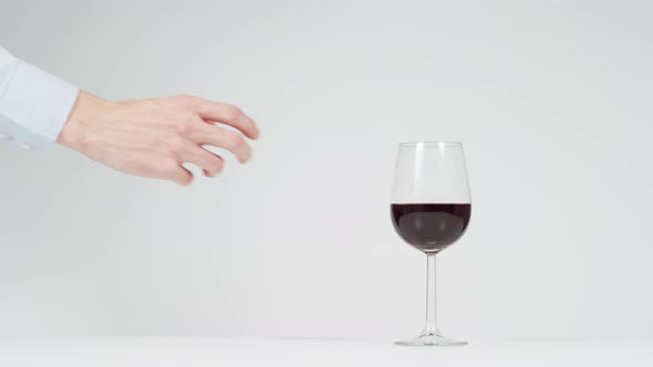 Hand taking a red wine glass