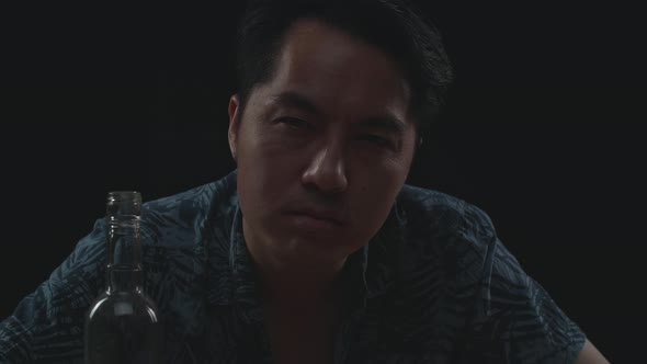 Close Up Of Drunk Asian Man With Vodka Looking At Camera In Black Background