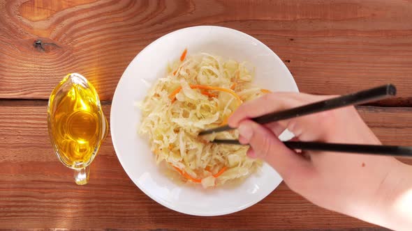 Eating Sauerkraut with asian chopsticks in hand. Pickled cabbage carrot Fermented by lactic acid