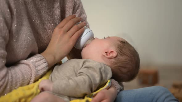 Adorable Kid Sucking Milk Formula From Bottle in Mommy Arms, Orthodontic Binky