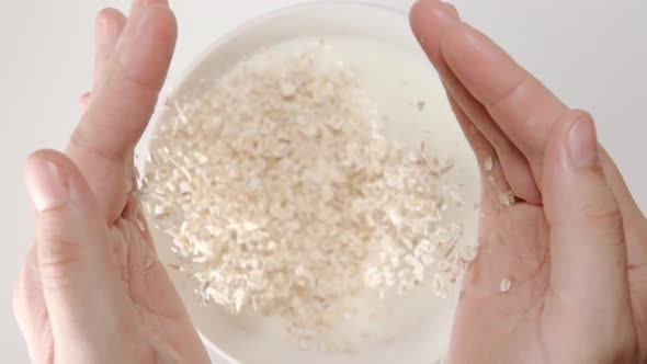 Oat Flakes Falls From A Human Hands To The Milk In A Dish