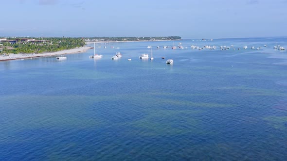 Aerial forward view over turquoise waters of Bavaro beach and moored boats at Punta Cana. Dominican