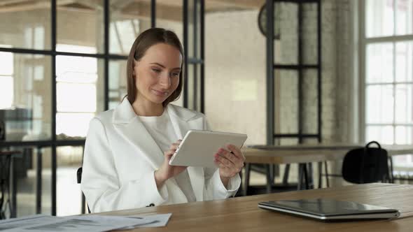 Focused Young Female Entrepreneur Using Her Digital Tablet While Sitting in the Office