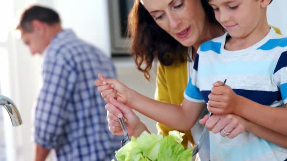 Mother and son mixing the salad in kitchen