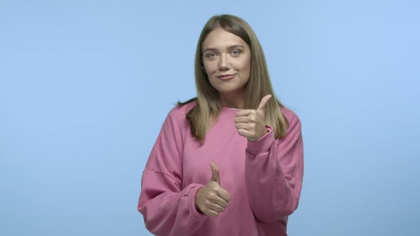 Cheerful Caucasian Female Model with Blond Hair Wearing Casual Sweatshirt Showing Thumbsup in