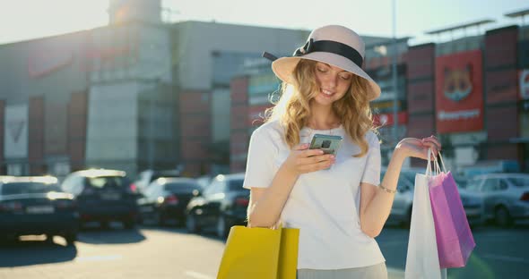 A Smiling Girl is Texting on Her Smartphone