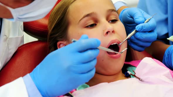 Mid-section of dentist and nurse examining a young patient with tools