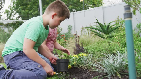 Happy caucasian boy with his brother gardening together in garden