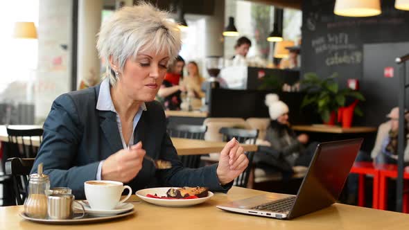 Middle Aged Woman Eats Cake in Cafe - Notebook (Computer)