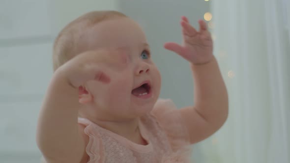 Cute Infant Girl with Blue Eyes Holding Hands Up and Smiling