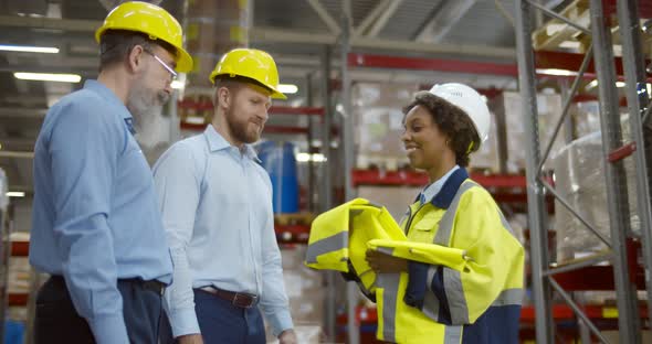 Africa Female Manager Meeting Businessmen and Giving Them Safety Vest in Warehouse