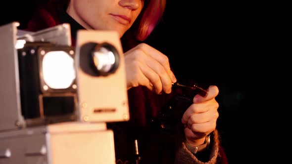 Closeup of an Old Fashioned Slide Projector and a Young Woman Inserting Its Supplements