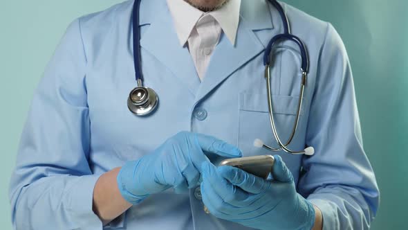 Doctor in Professional Medical Suit and Blue Gloves Checking Temperature By Digital Thermometer