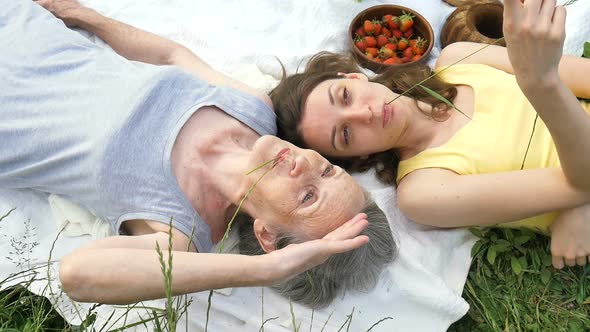 Beautiful Old Grandmother with Grey Hair and Face with Wrinkles is Lying on White Carpet with Her