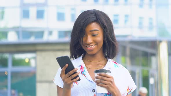 Elegant Beautiful African American Businesswoman Using Social Networks on Her Smartphone and Holding