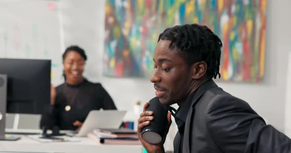 Darkskinned Coworkers Sit in the Company's Office in Front of Computers Dancing Singing Happy About