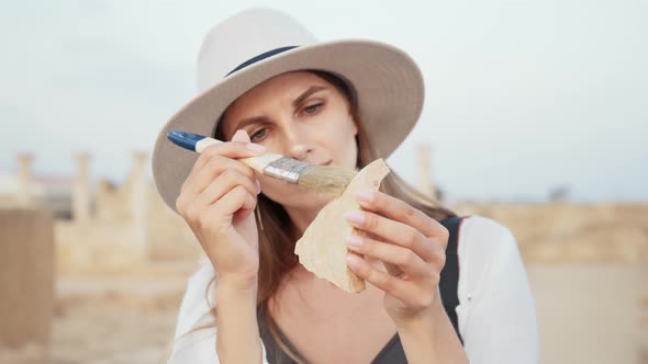 Archeologist Cleaning Piece of Ancient Columns with Brush