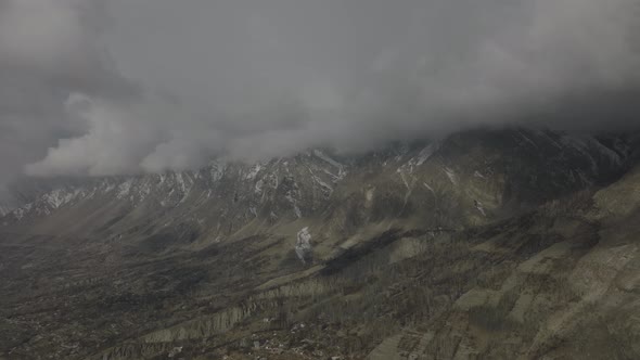 Aerial Flying Over Hunza Valley With Ominous Dramatic Clouds Hiding Mountain Peaks In Distance