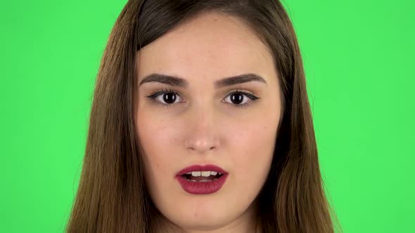 Beautiful Brunette Woman Looks at the Camera and Surprises. Close Up. Green Screen