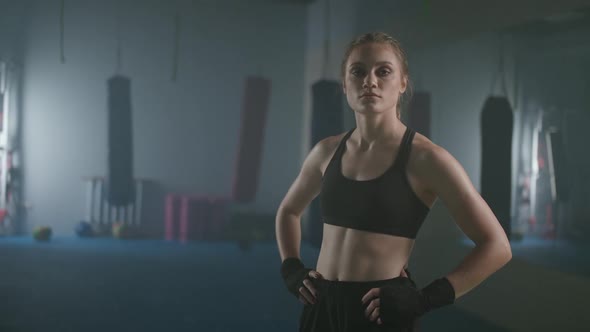 Portrait of a Serious Female Fighter Standing in a Boxing Gym and Looking Into the Camera Woman
