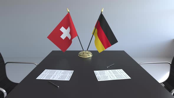 Flags of Switzerland and Germany and Papers on the Table alt