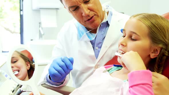 Dentist assisting young patient while brushing teeth