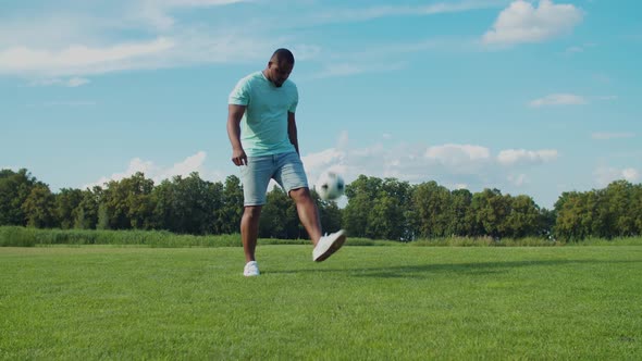 African Man Bouncing Soccer Ball on Leg Outdoors