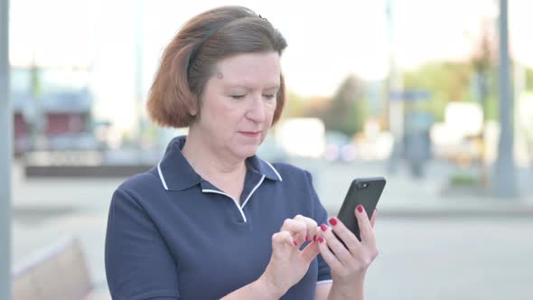 Old Woman Celebrating Win on Smartphone Outdoor