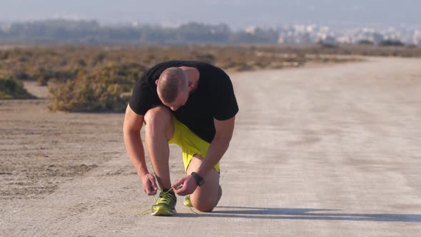 Sporty Man with Smartwatch Tying Trainers Shoe Laces Before Workout