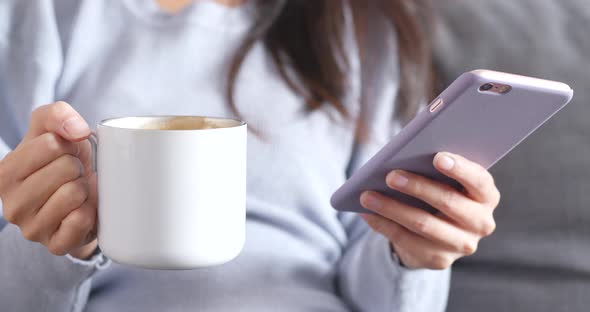 Woman use of mobile phone and enjoy coffee at home