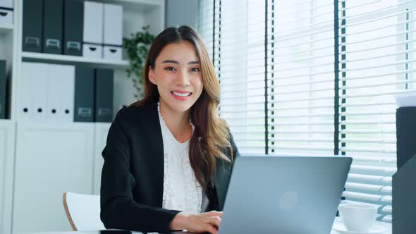 Portrait of Asian beautiful business woman  sit on table, smile while work in office workplace.