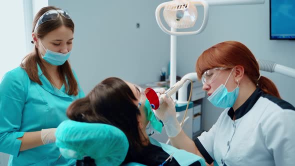 Female stomatologist and a nurse treating woman's teeth