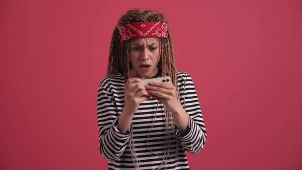Sad hippie woman playing digital game on phone