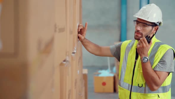 Professional Cargo Worker Talks on Portable Radio to Contact Another Worker