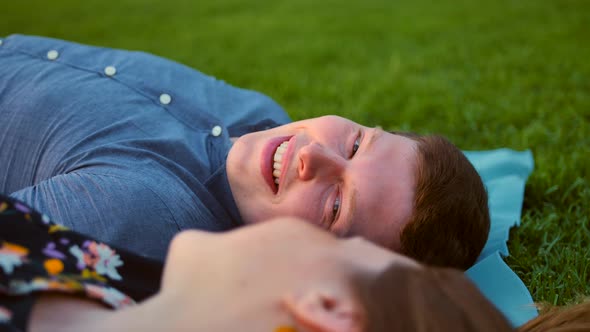 Happy Smiling Couple Relaxing on Green Grass. Male in Focus