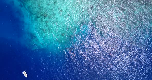 Wide fly over island view of a sunshine white sandy paradise beach and aqua blue water background 