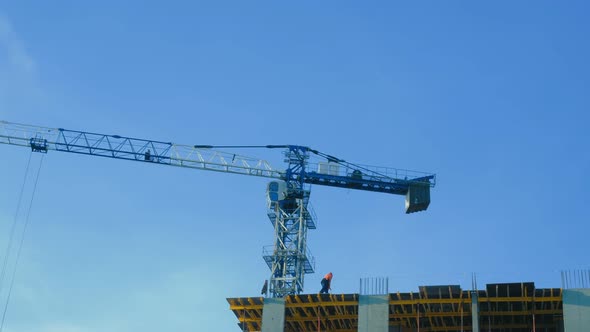 A Crane Near a Building Under Construction There is a Man in Special Clothing on the Building