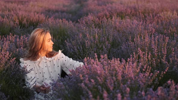 Pretty Blond Woman in a Dress Sitting in the Lavender Field