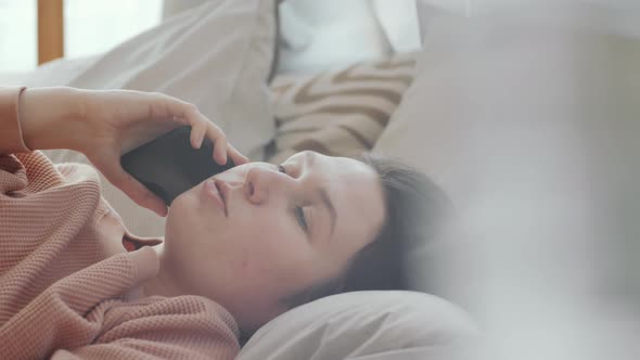 Woman Lying on Bed and Speaking on Mobile Phone
