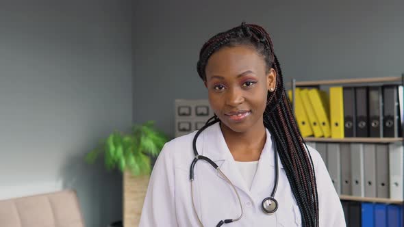 Portrait of Handsome African Female Doctor Wearing White Coat and Stethoscope Crosses Arms Standing