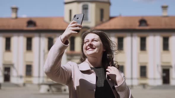 Happy Woman Looks Around Courtyard of Landmark Shoots Video on Phone