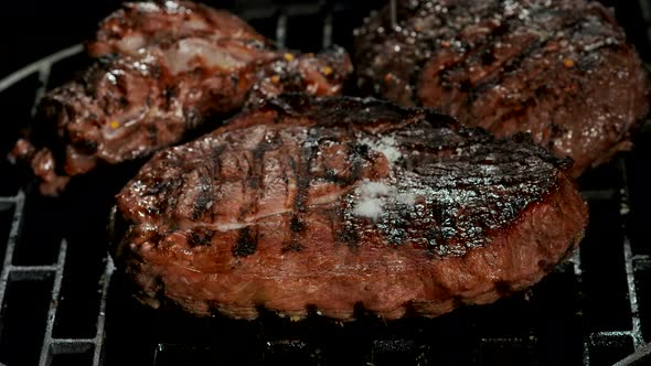 Closeup of the Salt Falling on the Delicious Beef Steak on the Grill