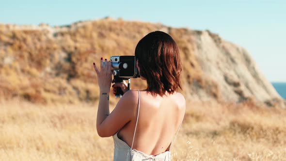 Beautiful Women Makes Shots with Vintage Camera in Yellow Countryside in Summer