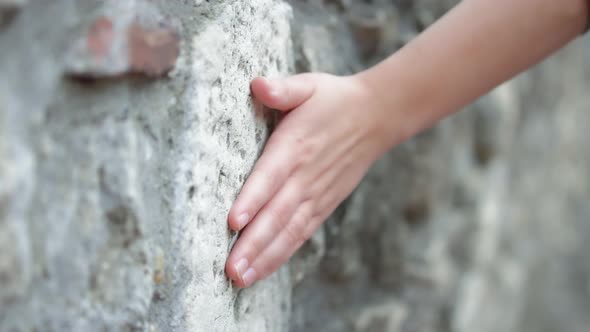 Woman sliding hand against ancient wall