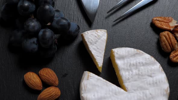 Sliced Cheese, Nuts, Grape, Honey and Knife on Shale Platter