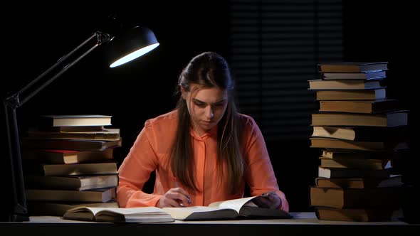 Girl Reads and Writes Information in a Notebook. Black Background